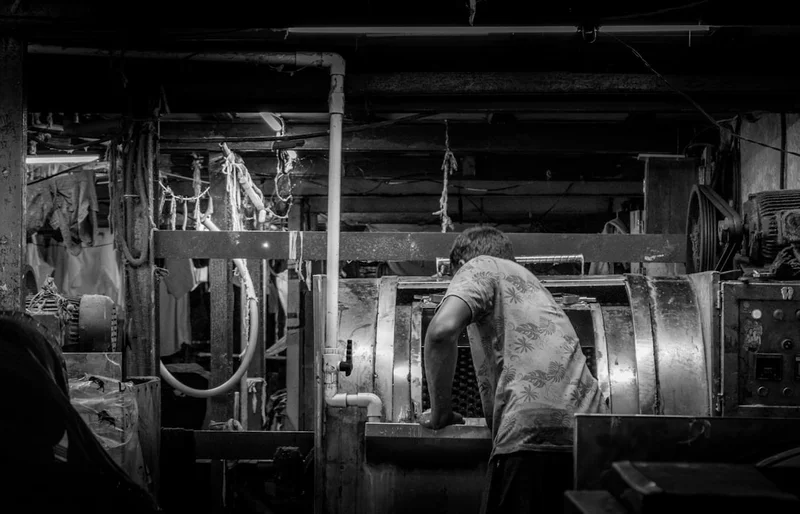 Un operatore carica indumenti in un tamburo di lavaggio industriale